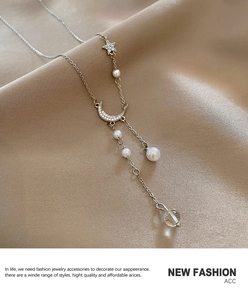 Macro detail of crescent moon and star pendants with pearls on silver chain