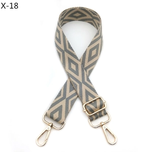 Detail of adjustable woven bag strap with grey geometric pattern and gold hardware