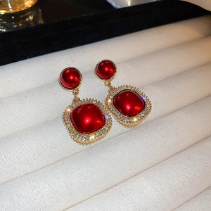Macro detail of vintage red square earrings with gold frame and sparkling rhinestones