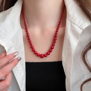 Vue détaillée d'un collier de perles rouges dégradées avec une finition brillante sur modèle