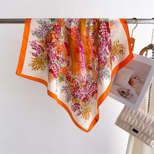 Detail of floral silk scarf in orange and cream hanging on a metal rack