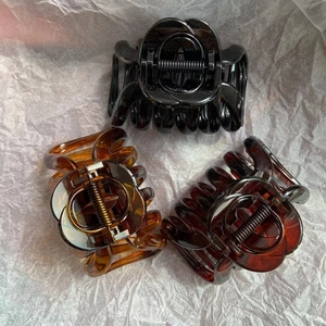 Close-up of three PC pumpkin hair claws in black, light amber, and dark amber colors
