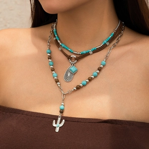 Close-up of bohemian layered necklace set with turquoise beads and silver cactus pendant