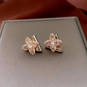 Macro shot of silver needle flower earrings with gold petals and inlaid zircons