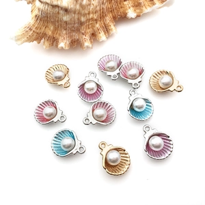 Detailed view of DIY shell charms with pearls in gold, pink, and blue enamel