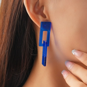 Macro side view of model wearing blue acrylic geometric drop earrings with silver needle