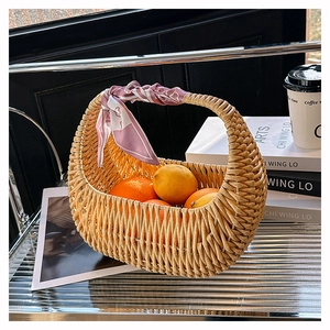 Detail of woven rattan basket bag with pink silk scarf handle and oranges inside