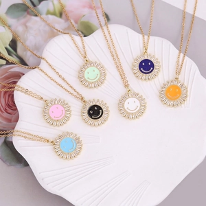 Golden smiley sunflower pendants with colorful enamel and cubic zirconia stones in a dish