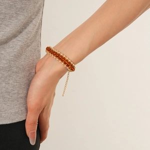 Detail of amber crystal and pearl beaded bracelet on wrist with gold chain adjustable link