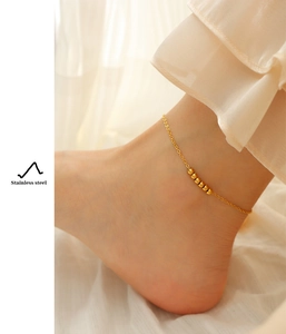 Detail of 18K gold-plated stainless steel anklet with beads on a model's ankle