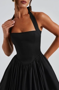Detailed view of the pleated waist design and smooth black woven fabric on the halter dress