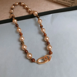 Detail of vintage necklace with champagne pearls, brown beads, and gold ring clasp