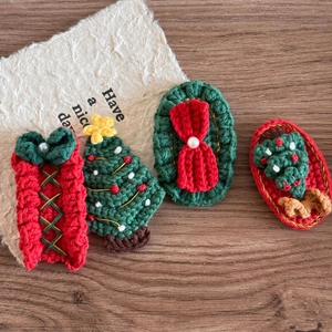 Handmade crochet Christmas hair clips with festive gift box and tree designs on wood background