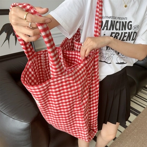 Detailed view of a red and white plaid fleece tote bag styled with a casual outfit