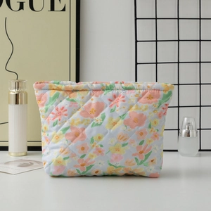 Detailed close-up of a quilted floral makeup bag with light blue fabric and orange flowers