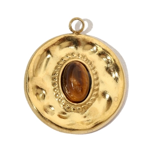 Detail of vintage gold stainless steel round pendant with brown tiger eye stone inlay