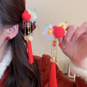 Detail of red knitted pompom hair clip with tassels and golden koi coin charms