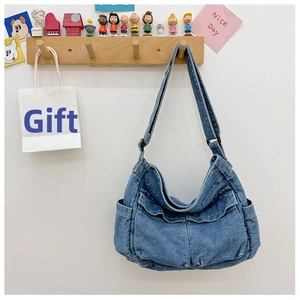 Detail view of denim crossbody bag with multiple pockets and adjustable strap