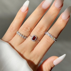 Close-up of three-piece silver chain ring set with red gemstone and pavé diamonds