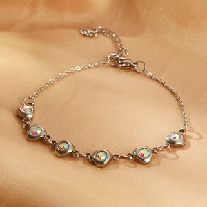 Macro shot of silver stainless steel bracelet with colorful heart-shaped zirconia on silk