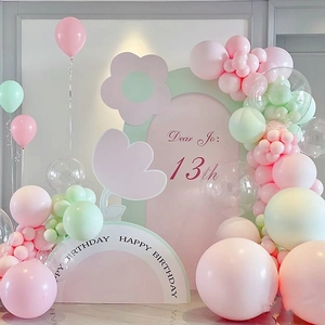 Macro detail of macaron balloon arch set with floral accents and birthday backdrop