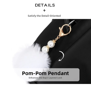Close-up of black nylon backpack featuring a white fur ball and pearl bag charm detail