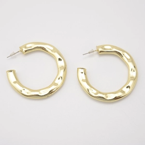 Close-up of gold hollow C-shaped earrings with a hammered wave texture finish