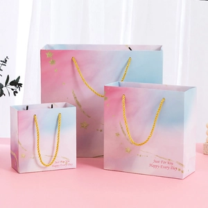 Set of three pink and blue gradient gift bags with gold stars and rope handles