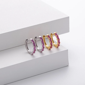 Macro shot of silver and gold 925 silver huggie earrings with pink zircon stones