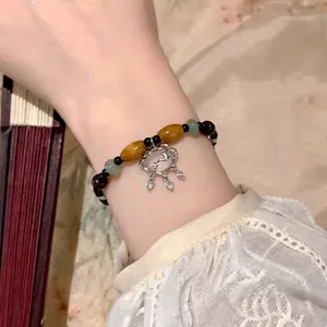 Close-up of vintage beaded bracelet featuring a hollow silver lock charm on wrist
