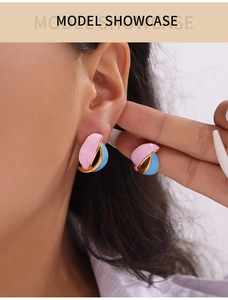 Close-up of model wearing vintage pink and blue enamel leaf earrings with gold trim
