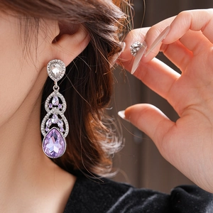 Vue macro de boucles d'oreilles argentées avec cristaux violets en goutte et strass