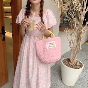 Détail du sac cabas matelassé rose avec motifs de cœurs et anses jaunes contrastées
