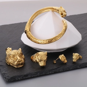 Golden tiger head jewelry set with bracelet and rings on black slate stone display