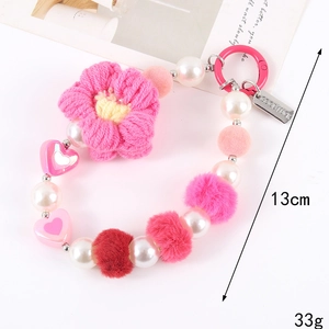 Detail of pink crochet flower keychain with beaded heart pearls and Good Luck metal tag