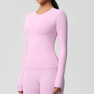 Vue latérale d'un haut de yoga rose à manches longues sur un mannequin dans un studio épuré