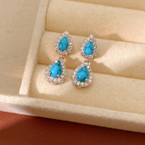 Detail view of vintage teardrop earrings with turquoise resin stones and zircon inlay