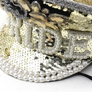 Detailed view of the sparkling gold sequins and BRIDE pearl lettering on the captain hat