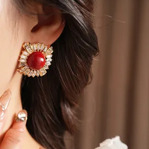 Vintage gold plated round earring with red center stone and rectangular zircon halo on ear