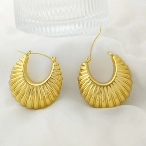 Close-up of golden U-shaped earrings with spiral texture on white satin background