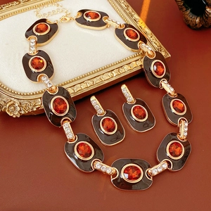 Detail of vintage gold necklace and oval amber stone earrings with brown enamel finish