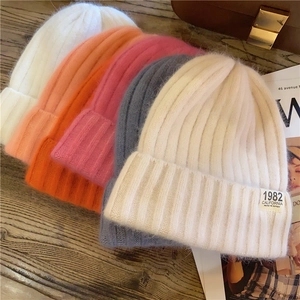 Close-up of assorted winter knit beanies with vintage woven labels on a wooden table