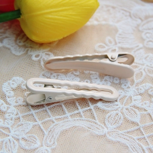 Detail of beige wavy metal hair clips on white lace background with yellow tulip floral decor