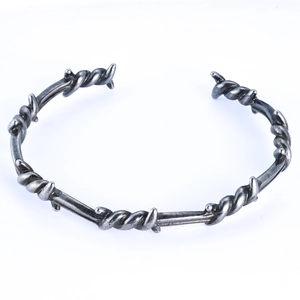 Close-up of punk style thorn pattern on an antique silver stainless steel open bangle