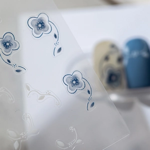 Adhesive nail stickers featuring blue and white floral patterns on translucent film