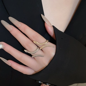 Close-up of three snake-shaped rings in gold and silver finish on a model hand