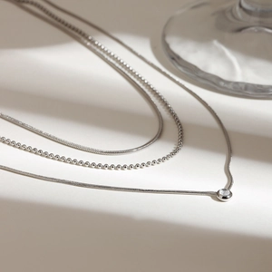 Detail of triple-layer silver titanium steel necklace featuring a sparkling crystal pendant