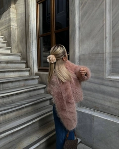 Vista posteriore di una giacca in ecopelliccia rosa da donna con jeans in stile street