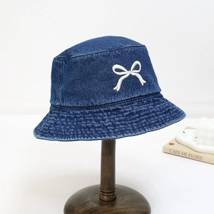 Chapeau bob en denim bleu avec nœud blanc brodé sur un support vintage en bois rétro
