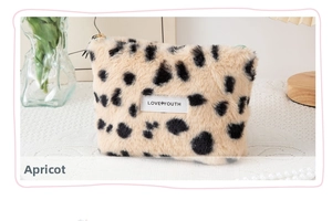 Detail of soft apricot plush cosmetic bag with black dots and LOVE YOUTH embroidery
